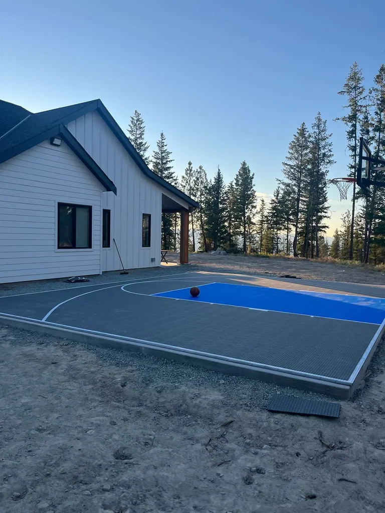 Grey basketball court beside a white house